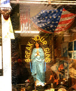 image of virgin mary statuette around which it says 'break your guns'.